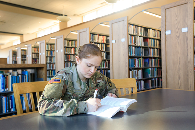 student in a uniform studying in the library