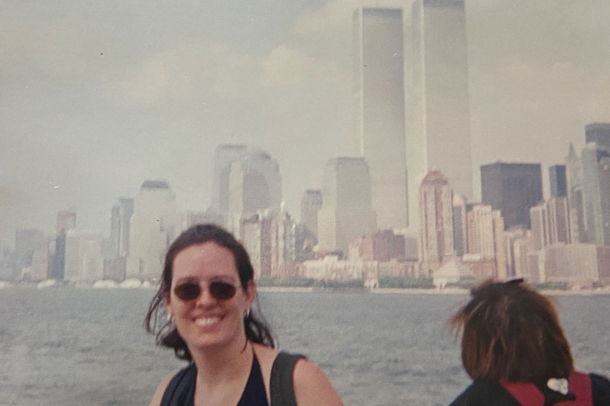 A younger Erin Grace poses in front of a skyline of New York City that includes the Twin Towers. 