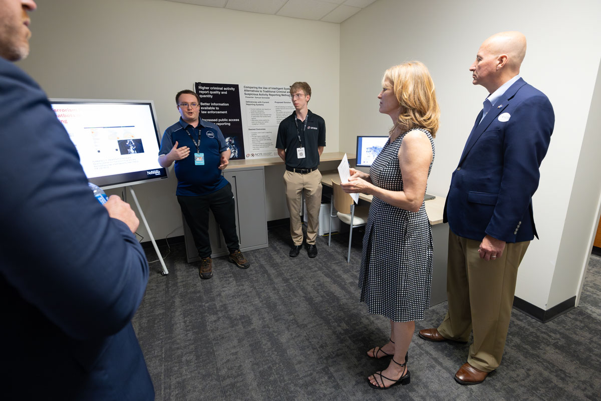 Bradley Corwin stands in front of a portable screen as he speaks with Sen. Pete Ricketts. 
