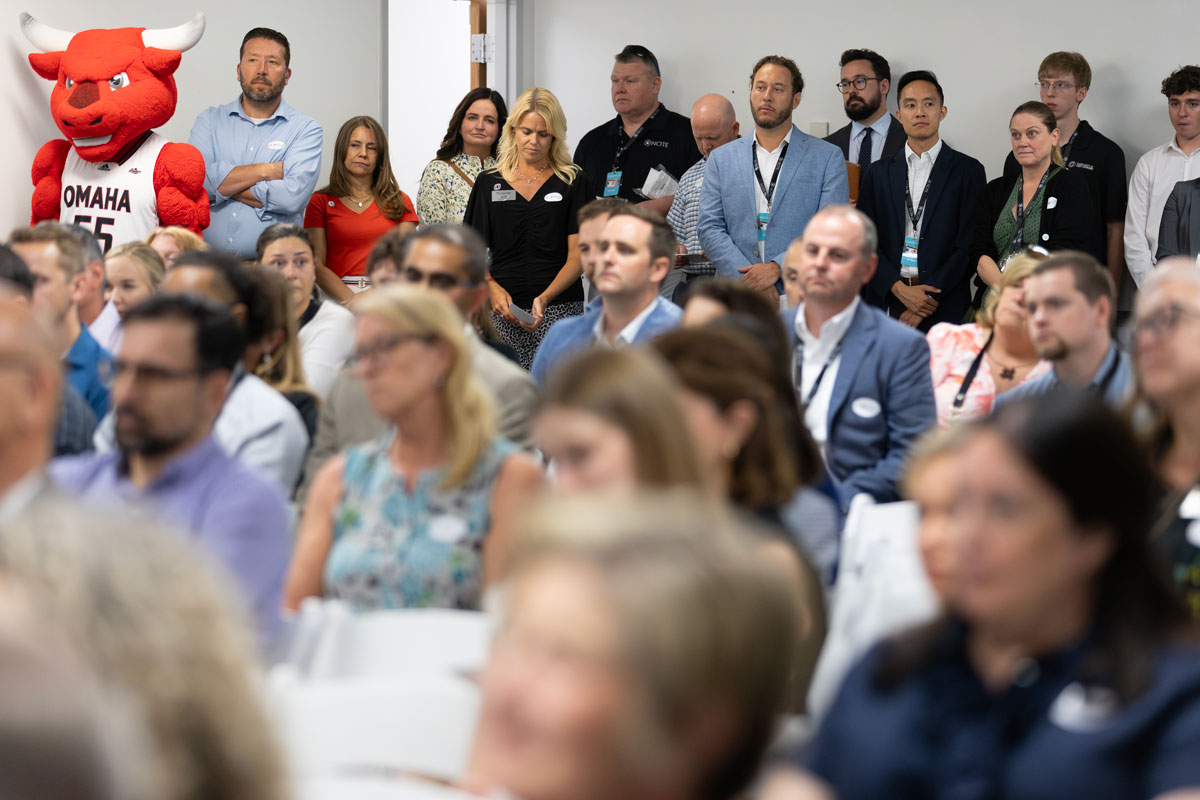 A wide shot of the crowd looking toward the camera, watching a speaker out of frame. 