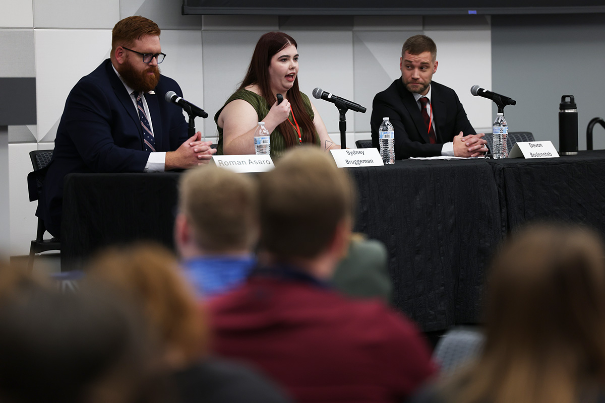 Three panelists participate in a discussion at the NCITE Law Enforcement Advisory Board Summit, with one speaker addressing the audience while the other two listen.