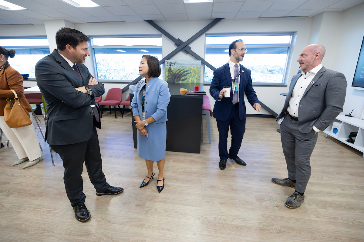 UNO Chancellor Joanne Li speaks with a government official while two other leaders converse nearby during a visit to NCITE headquarters in Omaha.
