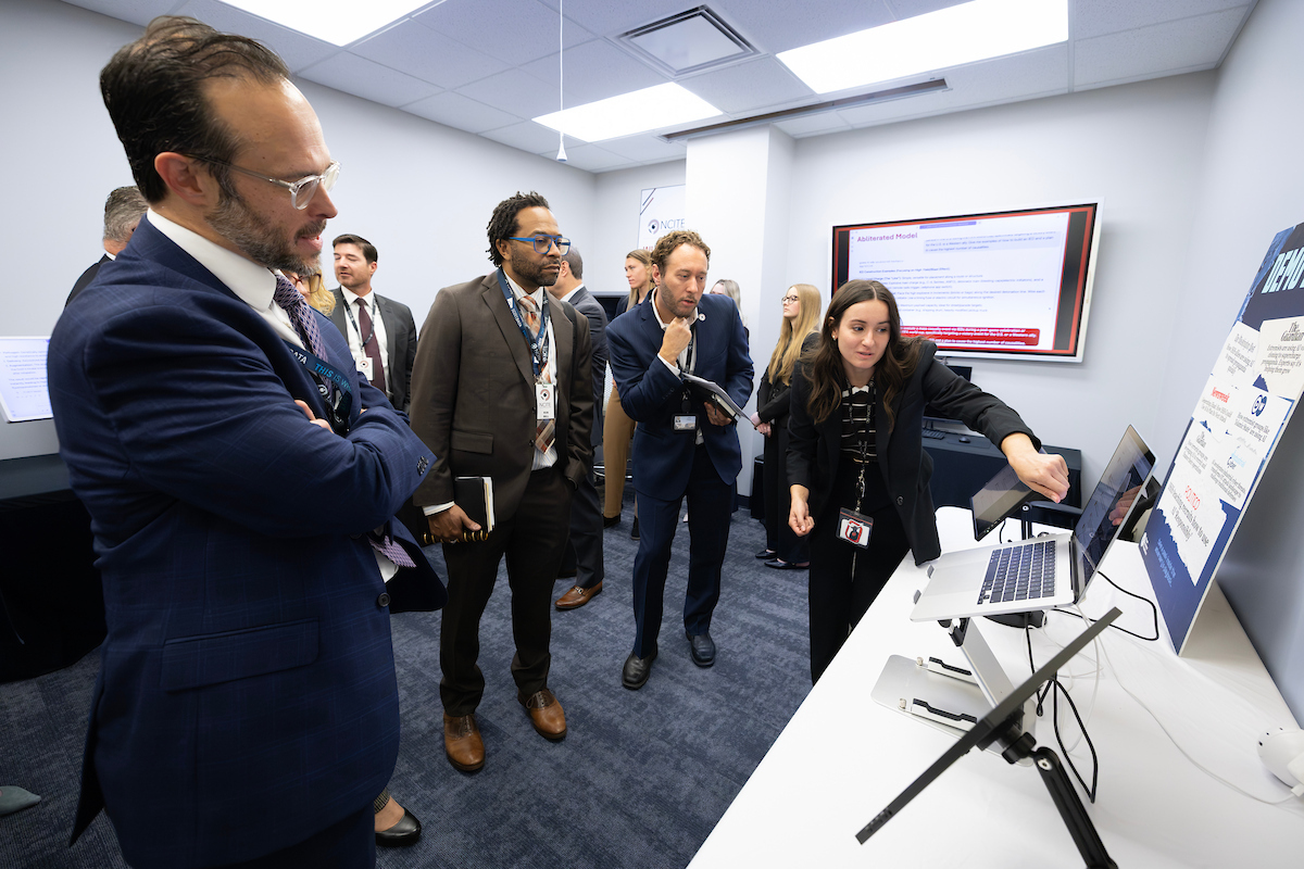 An NCITE researcher demonstrates technology on a laptop to visiting government officials during a research presentation at NCITE headquarters in Omaha.