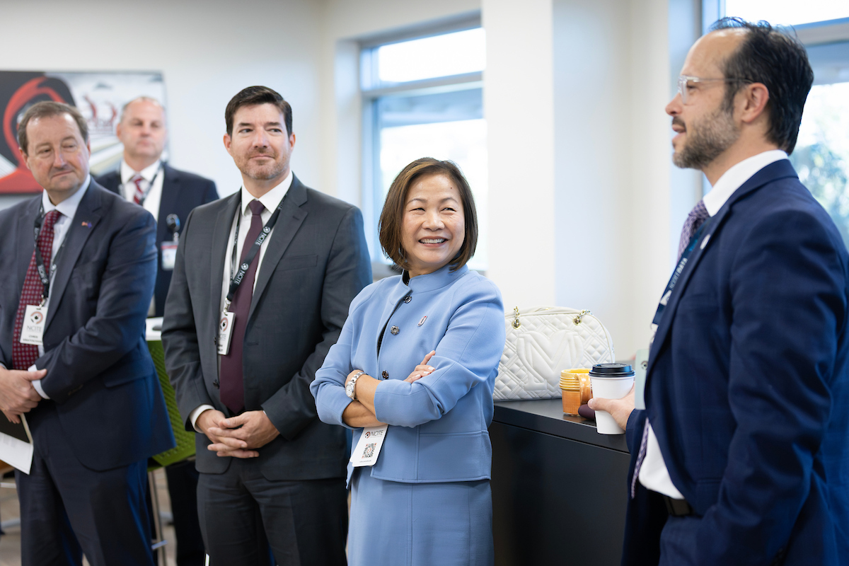 UNO Chancellor Joanne Li smiles while listening to Under Secretary for Science and Technology Pedro Allende man speak during a gathering of NCITE, university and government leaders at NCITE headquarters.