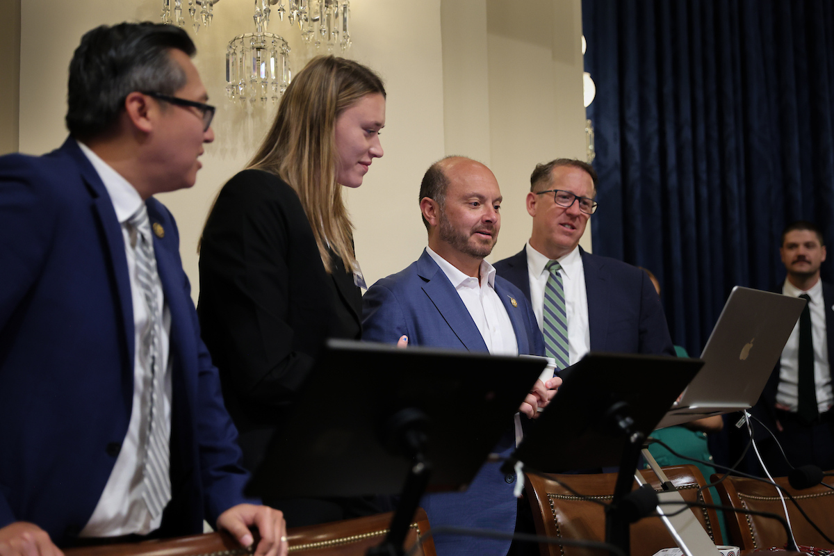An NCITE researcher demonstrates an artificial intelligence tool for members of Congress and staff during a briefing on Capitol Hill. Four presenters stand around a laptop and display monitors as attendees watch the live demonstration in a congressional hearing room.