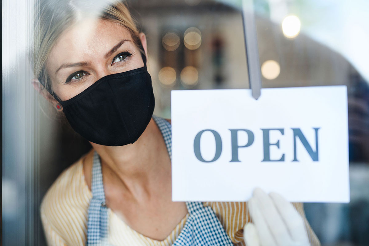 store owner with mask and open sign