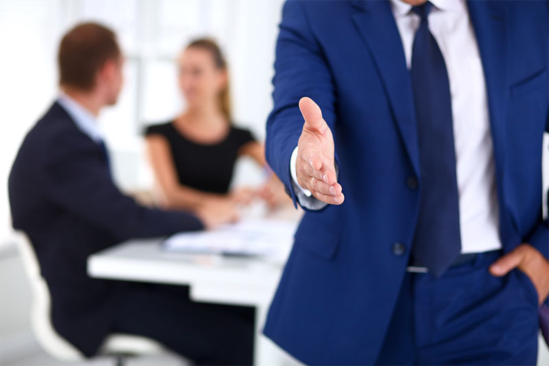 Blurred business man and woman with another male's hand reaching out to shake