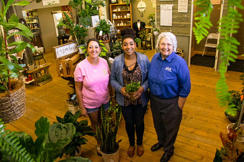 New Leaf owners standing in florist shop with NBDC staff member, Jennifer Wittrock
