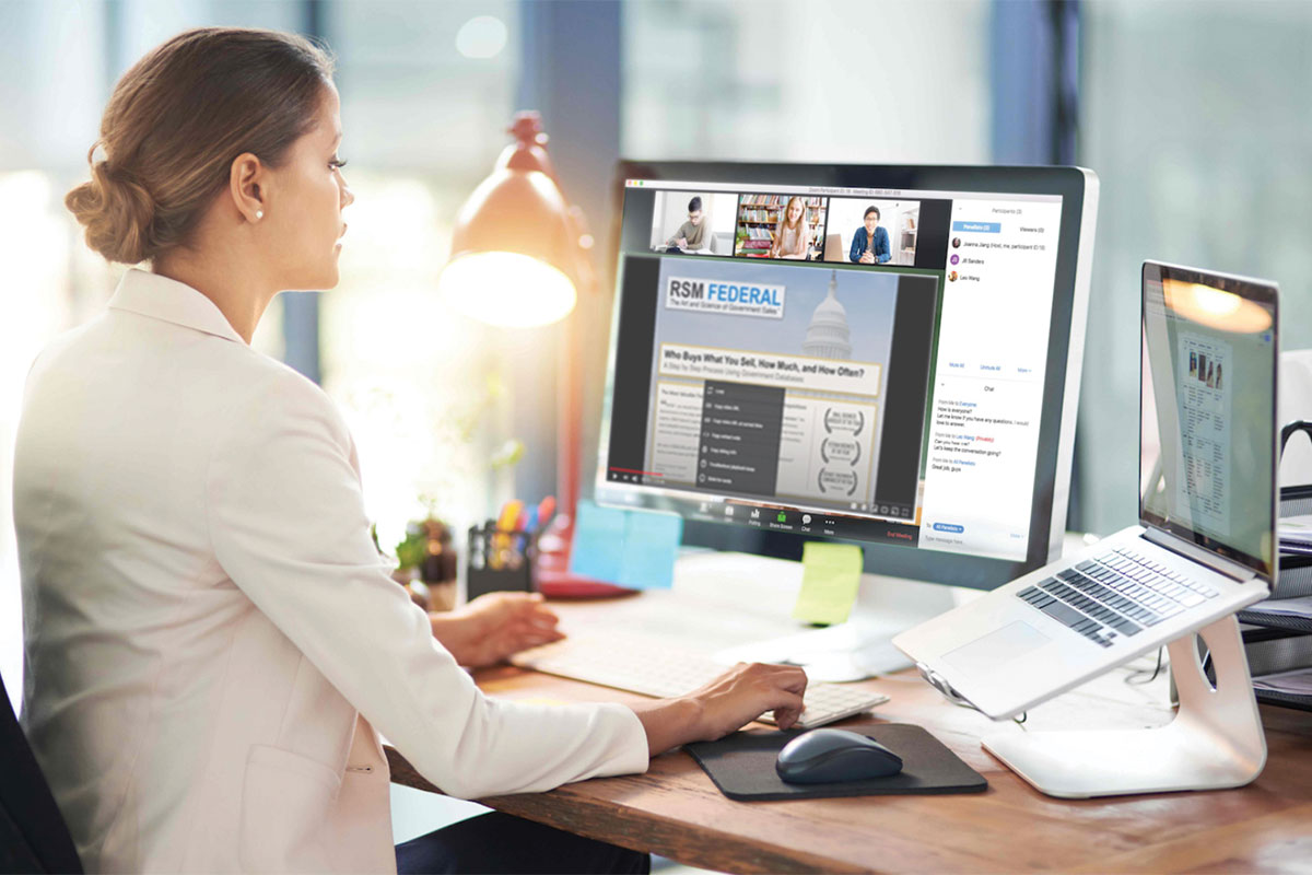 Female worker looking at both a desktop computer and laptop