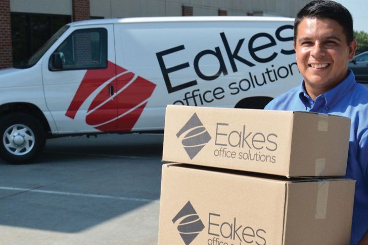 Eakes Office Solutions delivery van. Male worker smiling holding boxes.