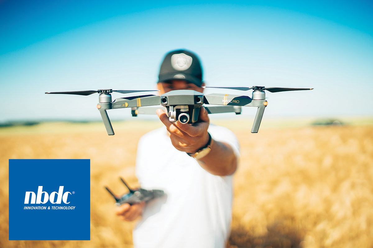 Man standing in field out of focus holding a drone.