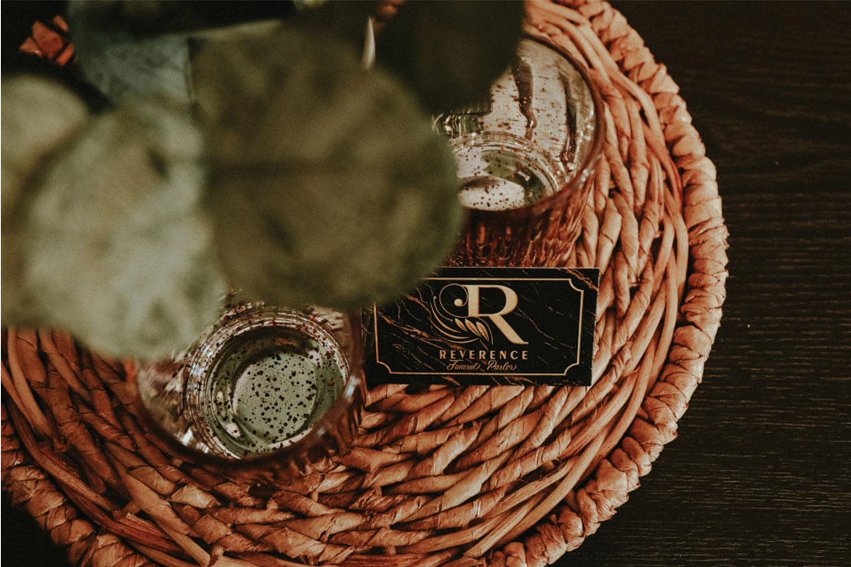 Composite image of Reverence Funeral Parlor business card, plant and decorative votives.