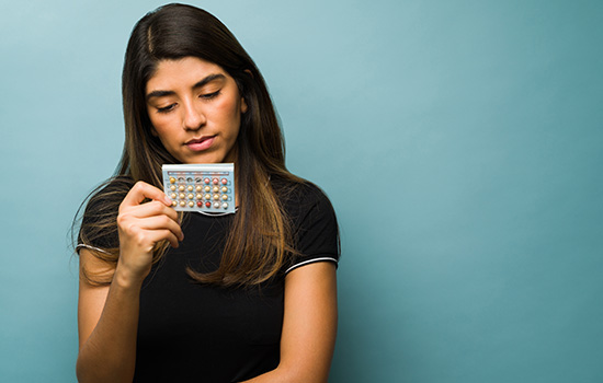 young woman looking at a blister pack of pills