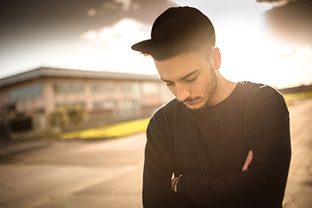 a young man walks through a parking lot, clearly in deep thought