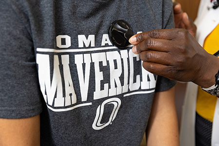 A hand holding a stethoscope against a patient's chest.