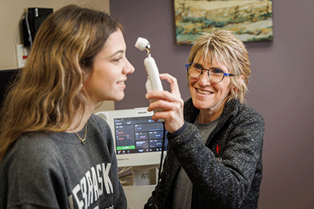 a health care provider checks the temperature of a student patient.