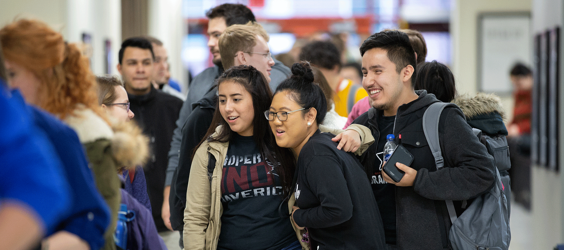 a diverse group of uno students stand together smiling in the student center.
