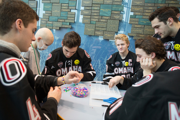 UNO Hockey players make beads with a patient. 