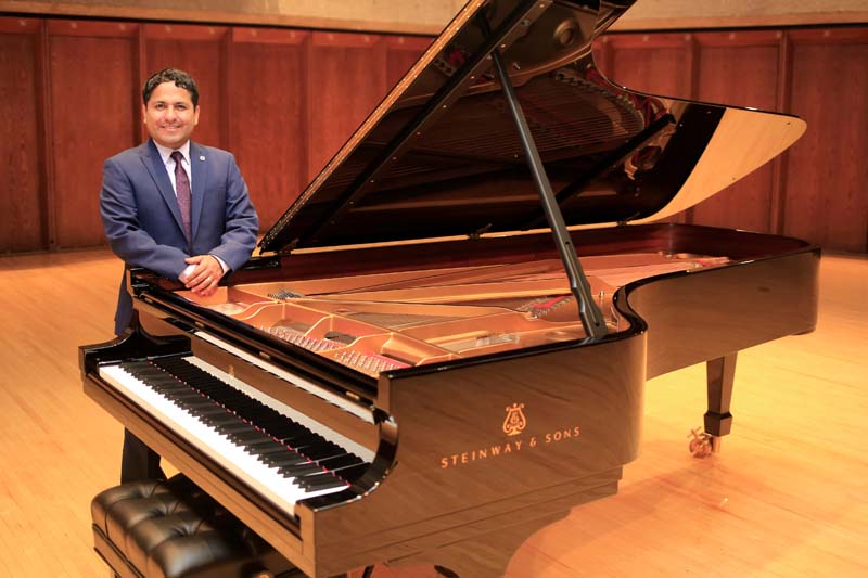 Washington Garcia stands next to the School of Music's newest addition, a Steinway and Sons grand piano