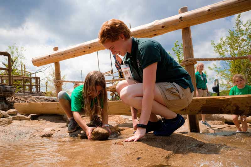 A play facilitator helps a young girl at the Children's Adventure Trails exhibit