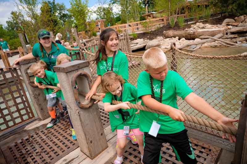 A play facilitator with Omaha's Henry Doorly Zoo and Aquarium helps guide a group of young children move a raft across a river