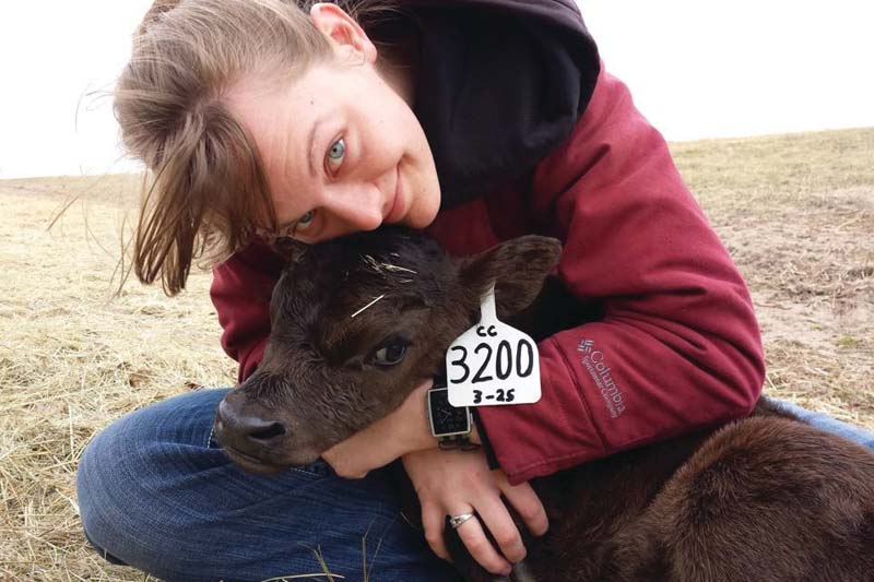 Rachel Ostrander Brownlee cradles a young calf on her family ranch