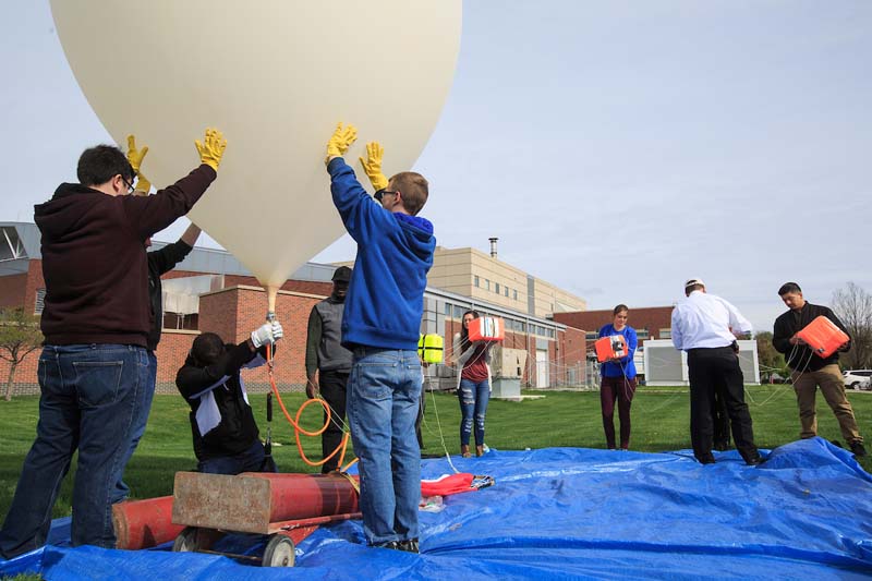 Students prepare a high altitude balloon to launch from the grass outside the Peter Kiewit Institute