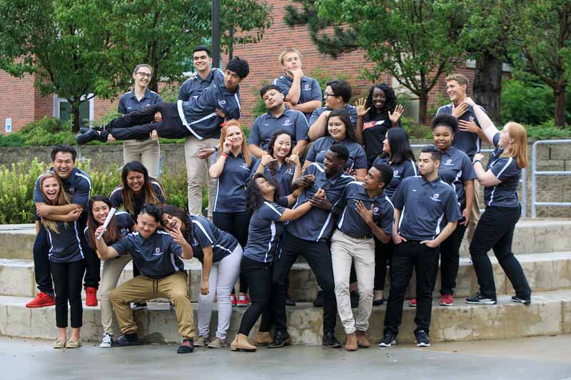 A group of TLC mentors pose for a playful photo on the Milo Bail Student Center plaza at the start of the 2017-2018 academic year