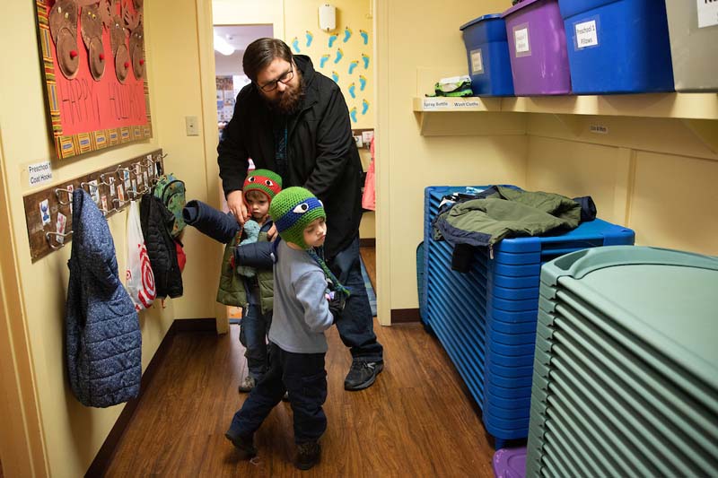 UNO student Brian Lee helps put on coats for his twin boys, Nate and Zach