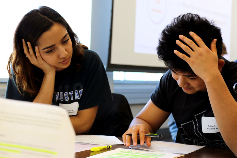 Two students review data points on the topic of hate speech as part of a deliberation exercised hosted at UNO's Barbara Weitz Community Engagement Center