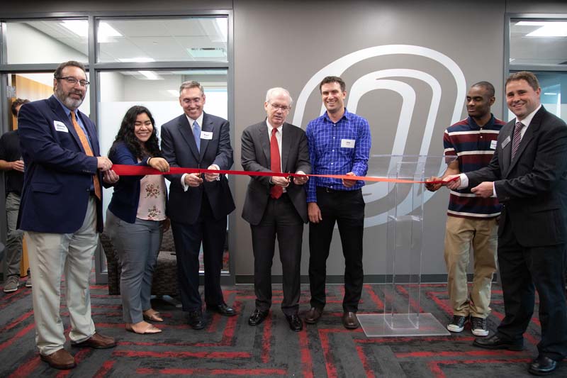 A group of administrators, faculty and students stand together to cut a ceremonial ribbon dedicating the opening of the UNO Health Careers Resource Center