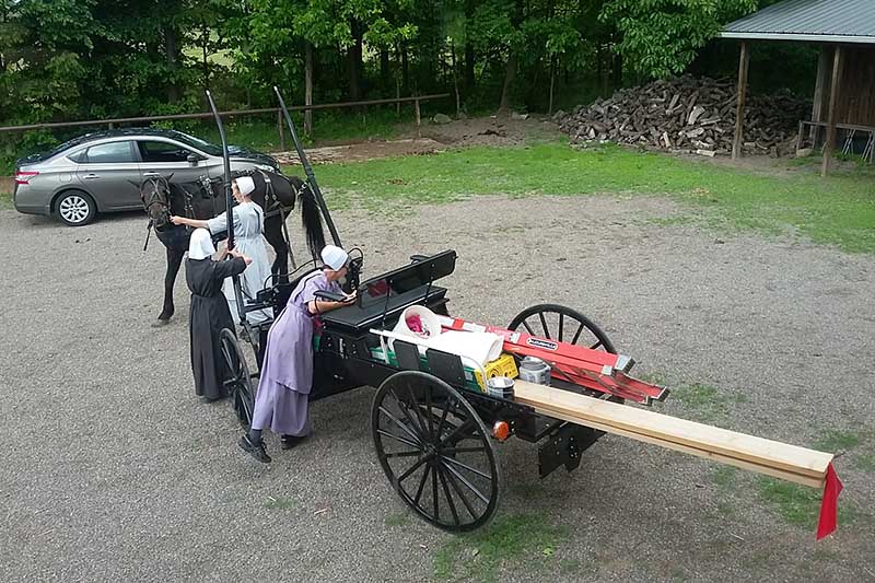 Amish women load a cart with supplies at a settlement in upstate New York