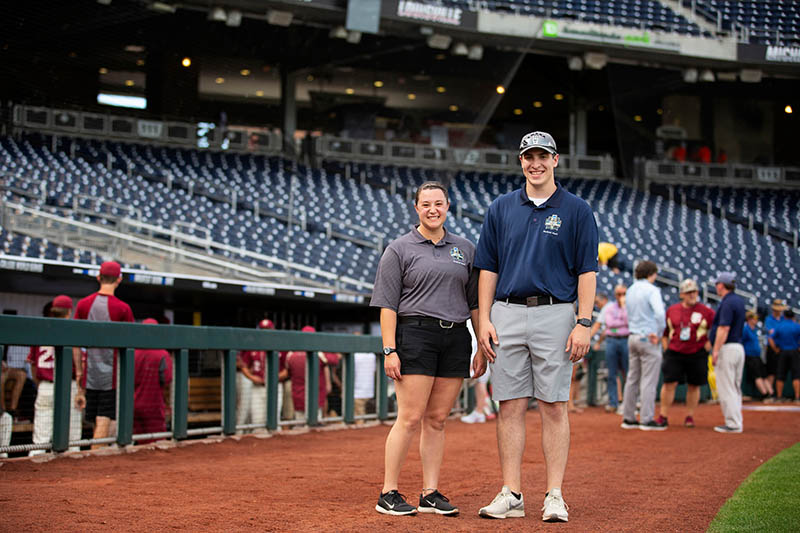Jacqui Gutierrez and Tyler Gregurich stand near the first base dugout at TD Ameritrade Park at the 2019 College World Series