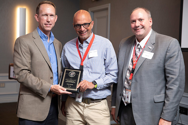 Matt Tracy presents an award for Jamie Honke, accepted by Joe Kilzer and Superintendent Dr. Mark Adler