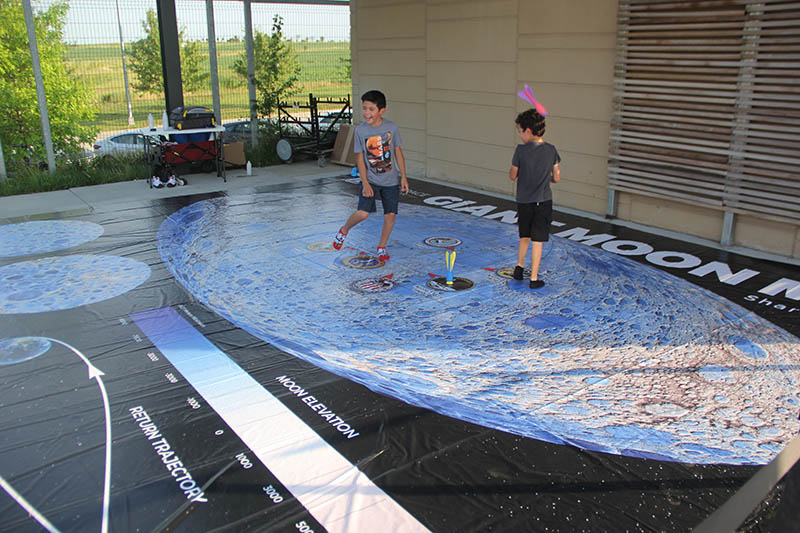 Future astronauts? Two boys play with foam rockets while standing on a giant vinyl map of the moon.