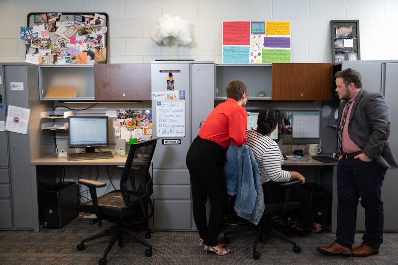 A group gathers around a computer in the Midlands Sexual Health Research Collaborative office.