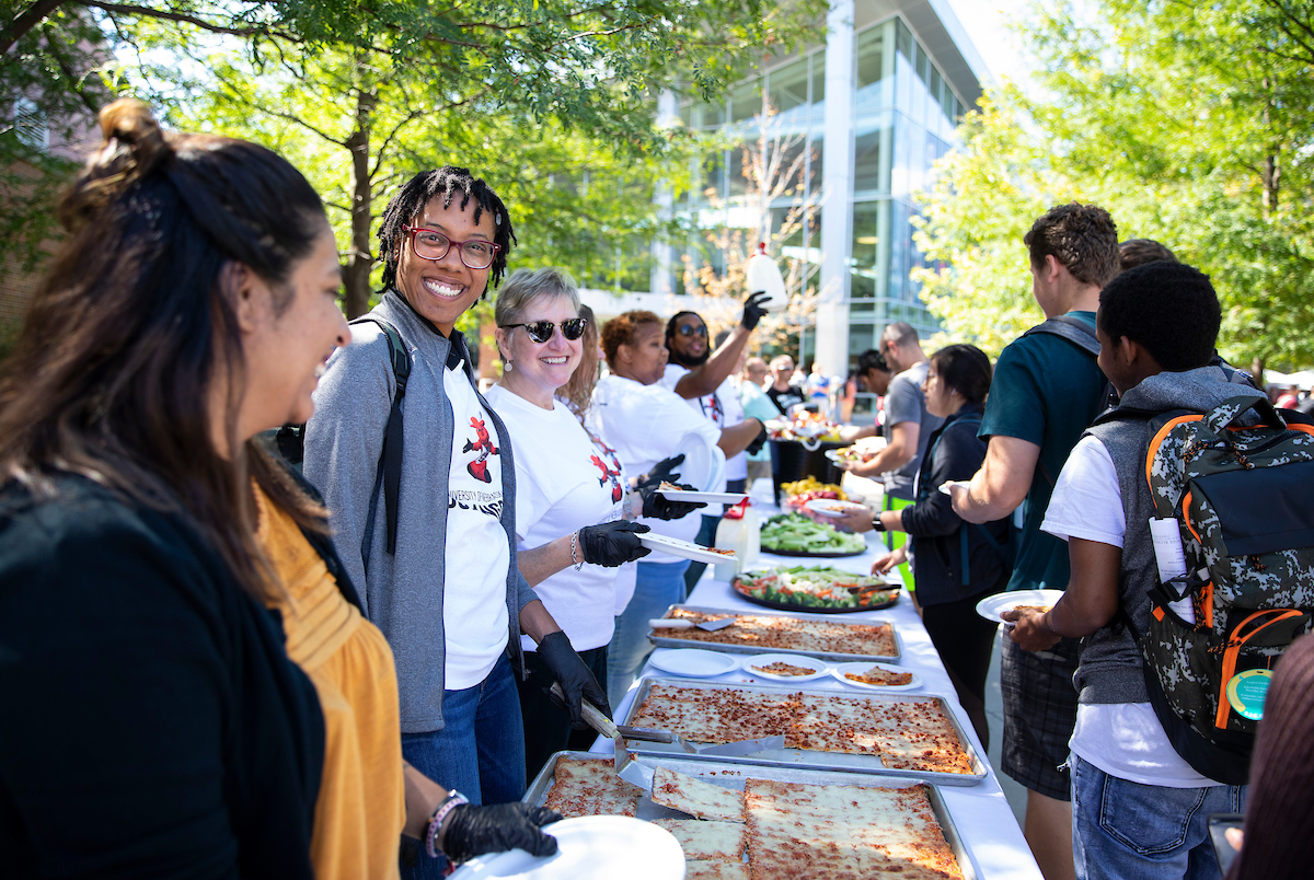 Staff volunteers hand out slices of pizza during Durango Days