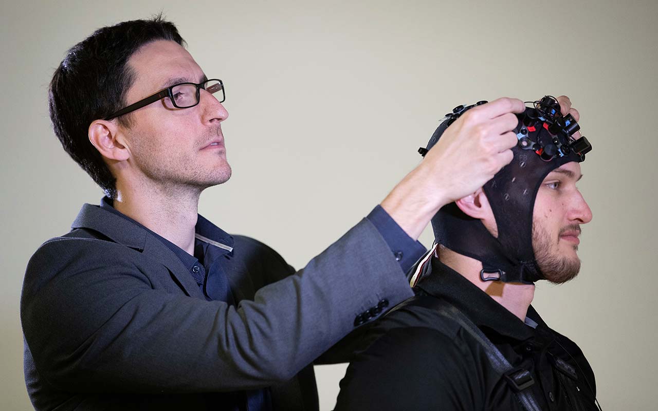 Assistant Professor Vivien Marmelat, Ph.D., looks over sensors placed on a man's head as part of research related to Parkinson's disease being conducted in the Biomechanics Research Building at UNO.