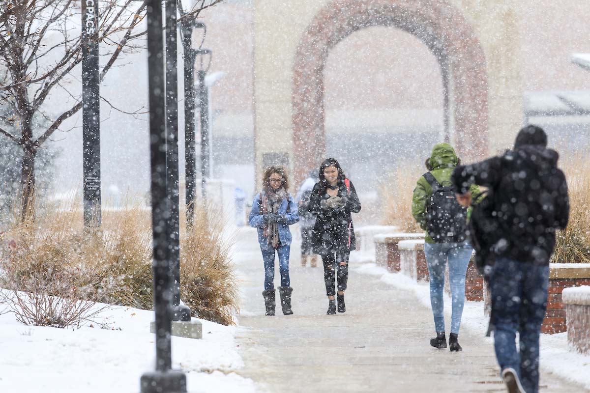 Students walk across campus as snow falls