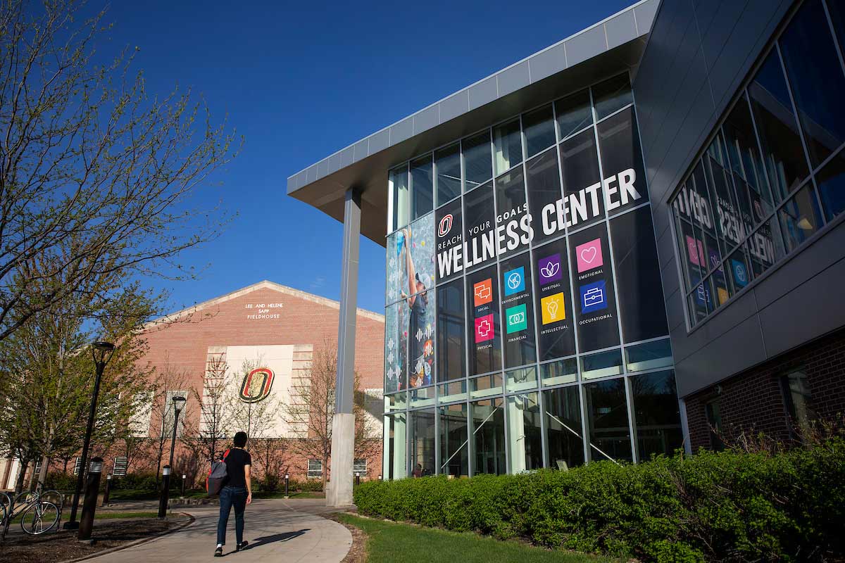 A student walks towards the Health and Kinesiology building on campus.