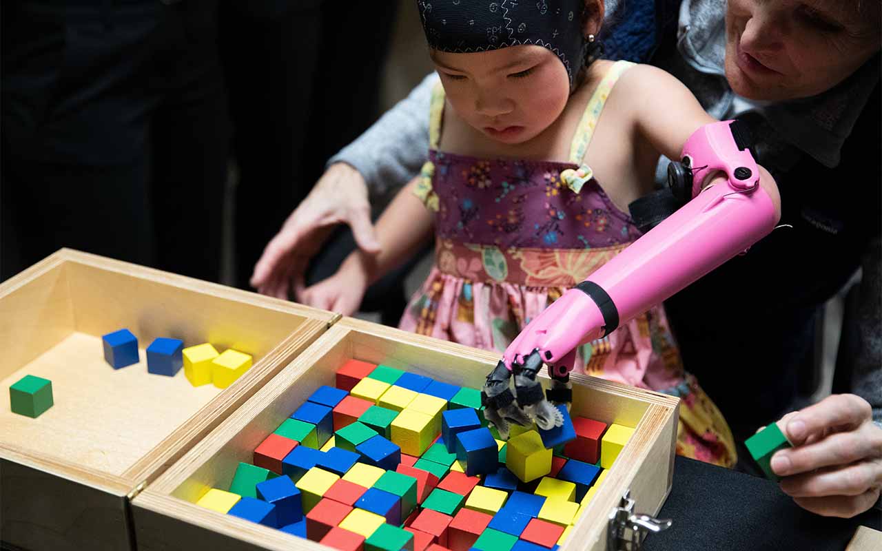 With the guidance of Jorge Zuniga, Ph.D., Rue Gillespie, 4, uses a prosthetic arm 3D-printed at UNO to complete exercises that require precise movements.