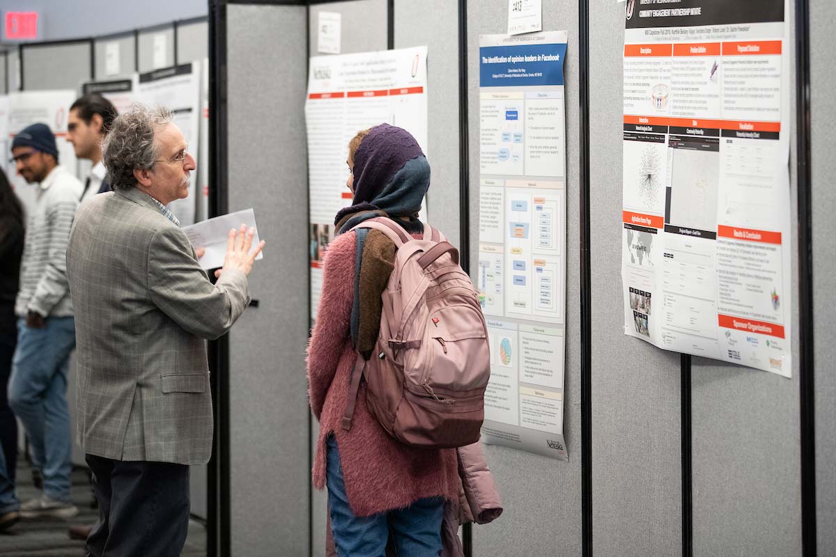 A faculty member talks with a student about their poster presentations.