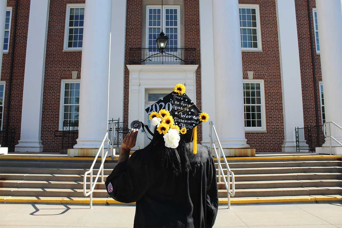 Lashaye Blake-Cooks, a first-generation graduate, holds her medallion in front of Arts and Sciences Hall on the UNO campus.