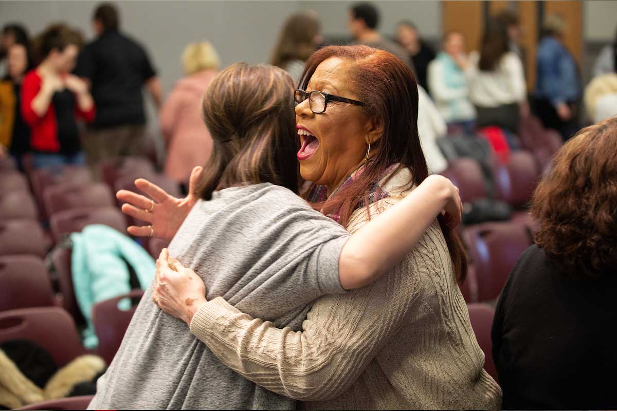 Two staff members embrace during a Staff Advisory Council event in 2019.