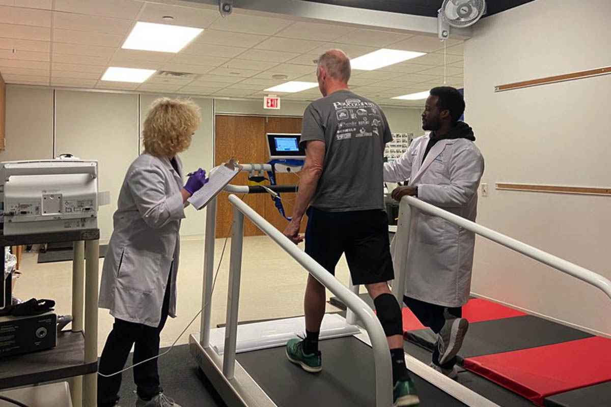 A research participant undergoes testing, walking on a treadmill while researchers record metrics and observations nearby, as part of a study on the effectiveness of a novel antioxidant as part of therapy for patients with peripheral artery disease.