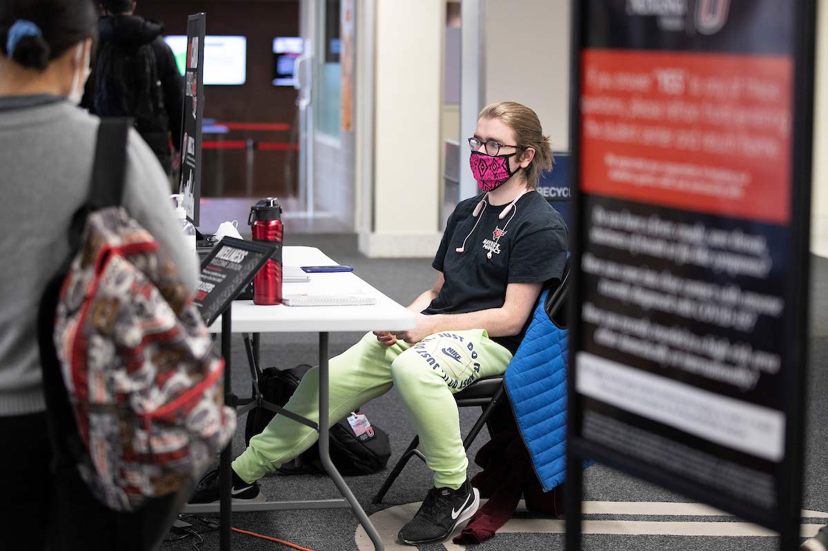 A student checks guests in at the Milo Bail Student Center Wellness Welcome Station.