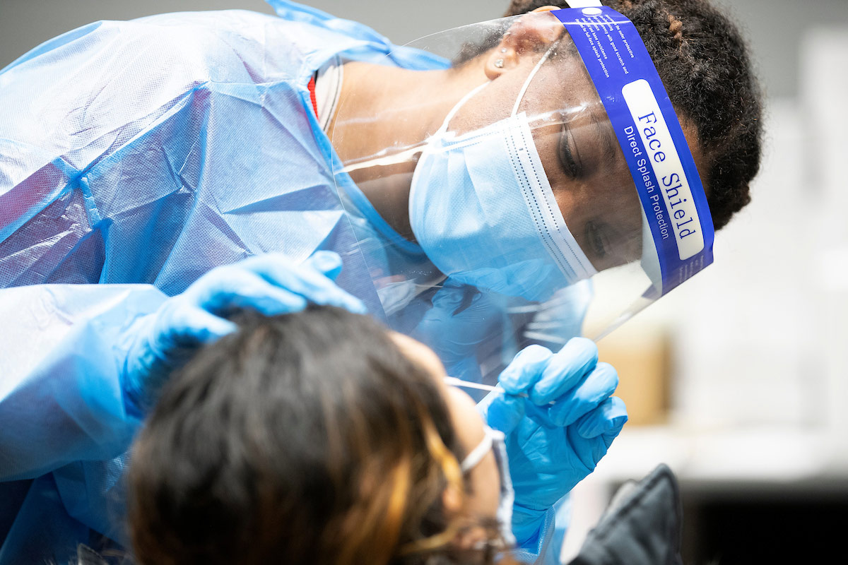 A medical professional in PPE administering a COVID test