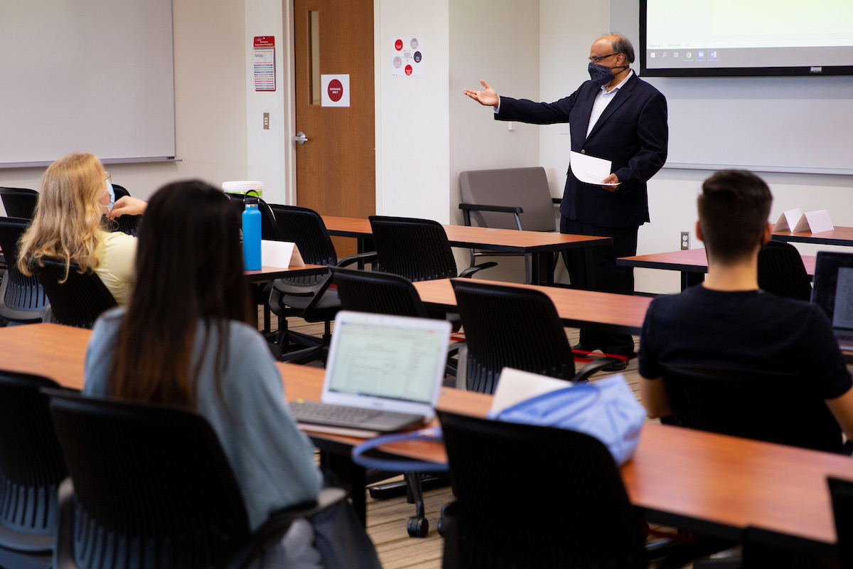 A faculty member teaches with a plastic visor as part of an IT Innovation course.