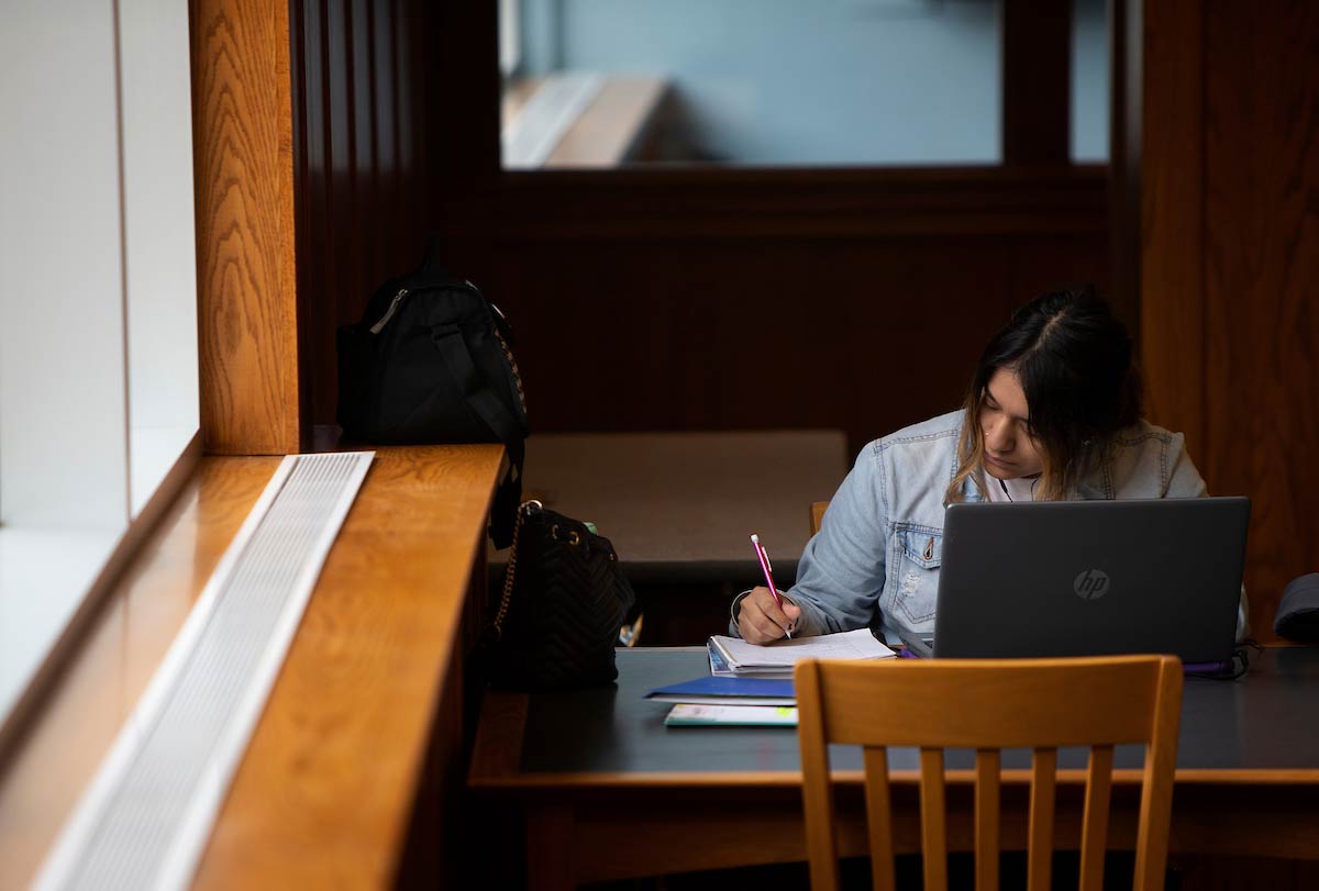 Student sits by a window on the second floor of the Criss Library