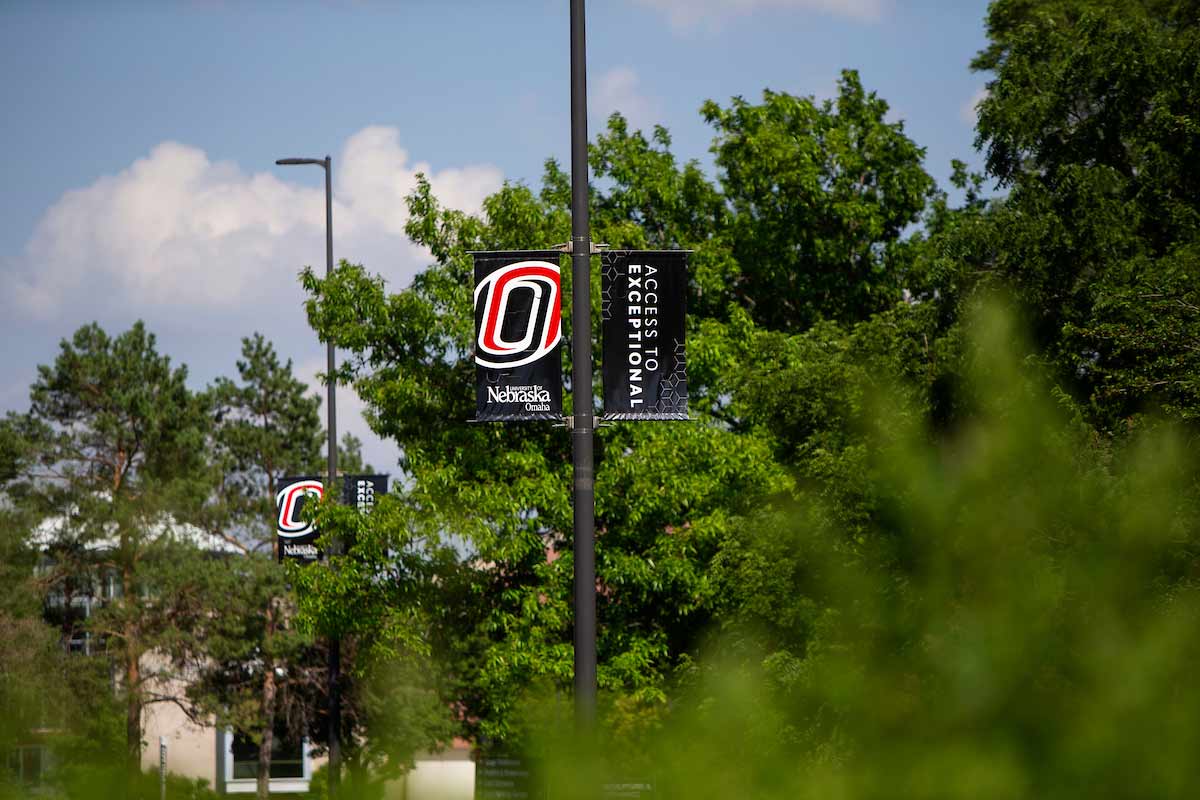UNO's "Access to Exceptional" pole banners framed by large, green trees
